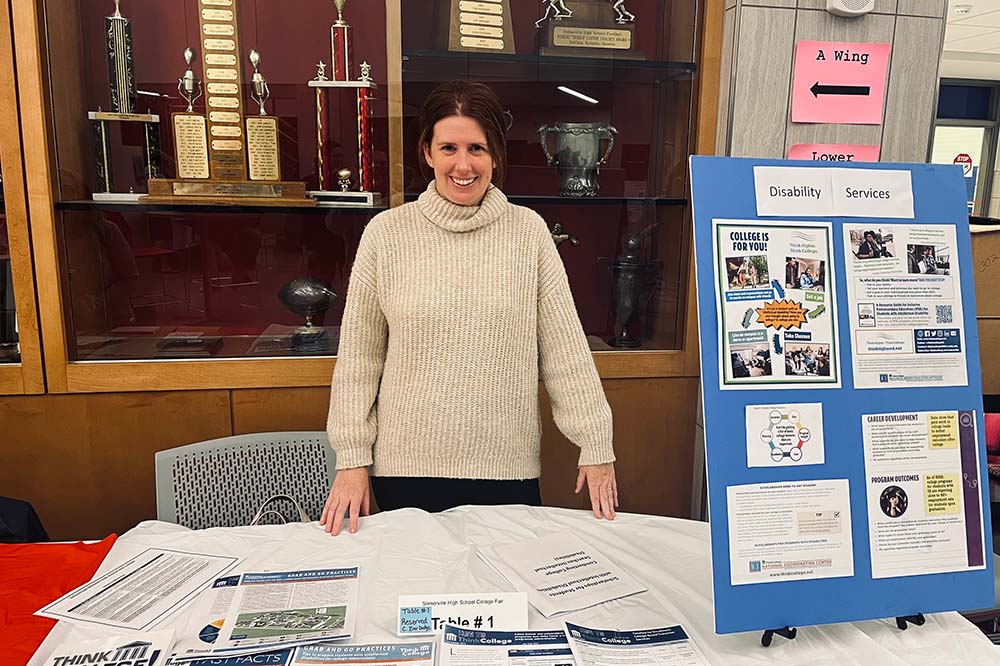 A young women stand in front of a presentation table