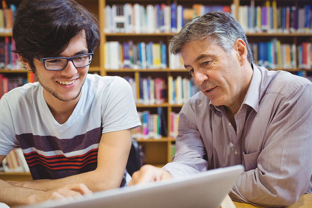 a instructor working with a student over a laptop