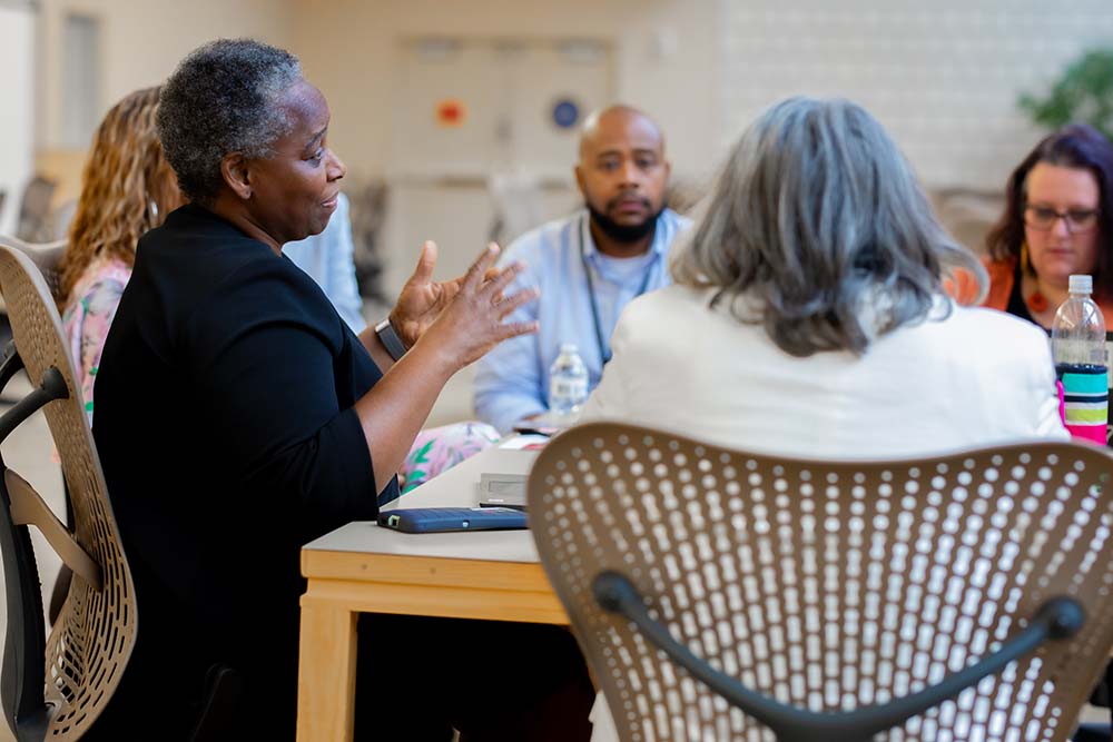 Black women with graying hair leads a meeting